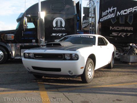 1968 Ford Mustang - A white Dodge Challenger with a black hood scoop is parked in front of a Mopar semi-truck.