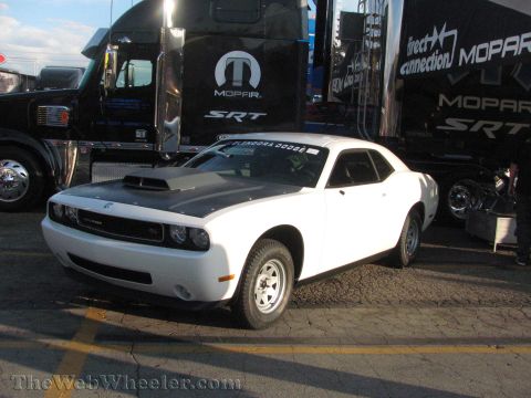 1968 Ford Mustang - A white Dodge Challenger with a black hood scoop is parked in front of a Mopar semi-truck.