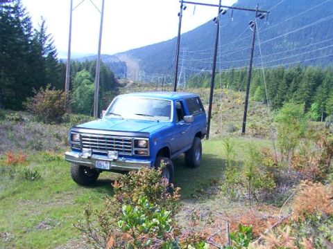 1980 Ford Bronco - Blue 1980 Ford Bronco parked off-road with power lines and mountains behind it.