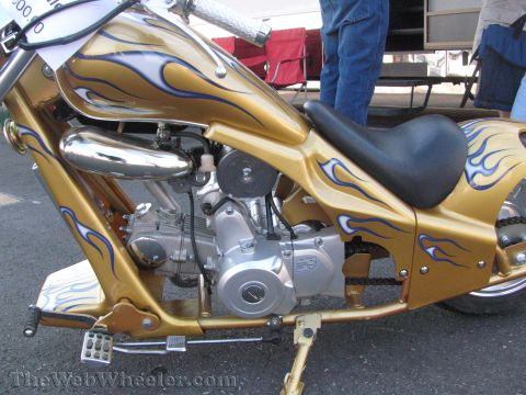 1968 Ford Mustang - A gold custom motorcycle with blue flame graphics is shown from the side, focusing on its engine and seat.