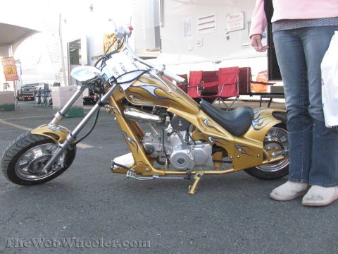 1968 Ford Mustang - A gold custom chopper motorcycle with flame decals is parked on asphalt, with a person standing nearby.