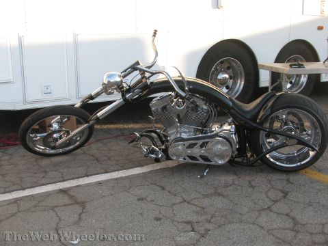 1968 Ford Mustang - A custom chopper motorcycle is parked in front of a white trailer, its intricate chrome engine and custom frame.