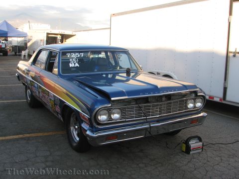 1968 Ford Mustang - A blue Chevrolet sedan, likely from the mid-1960s, sits parked with racing decals and a battery charger nearby.