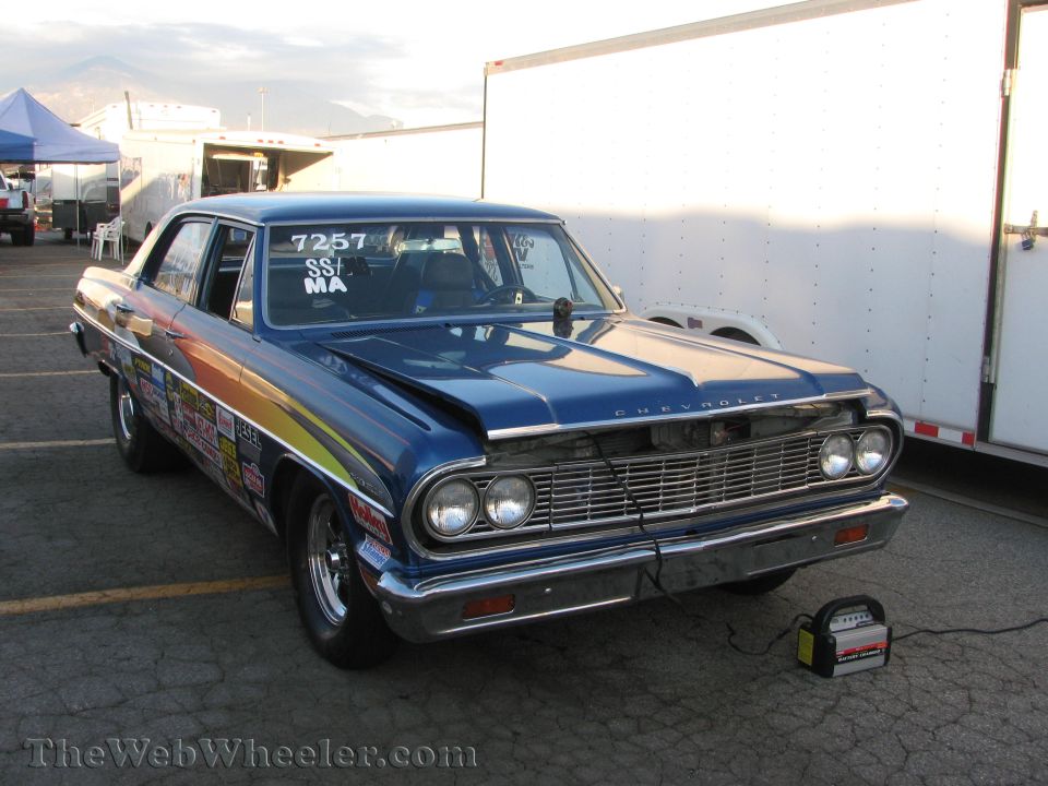 Blue Chevrolet sedan with racing decals on the side and number 7257 on the windshield. A battery charger is connected to the car