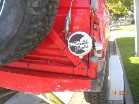 1985 Ford Bronco - Rear view of a red vehicle showing a spare tire and Pro-Comp sticker. The vehicle appears to be on a trailer.