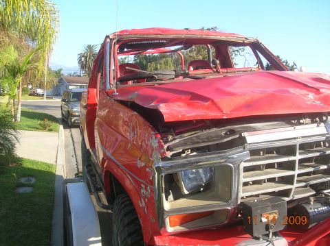 1985 Ford Bronco - This heavily damaged red truck shows significant front-end collision damage, including a crumpled hood and missing windshield. A date stamp…