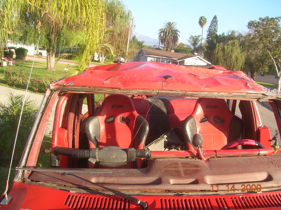 Interior view of a red vehicle with racing seats and a damaged roof