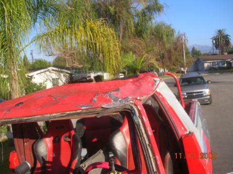 1985 Ford Bronco - Interior view of a damaged red vehicle with racing seats; a silver SUV is visible in the background.