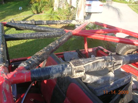1985 Ford Bronco - Interior view of a vehicle's red roll cage, covered in black tape and dirt.
