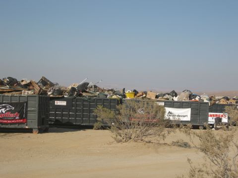 1986 Ford Bronco - Large dumpsters are filled with trash and debris in a desert environment.