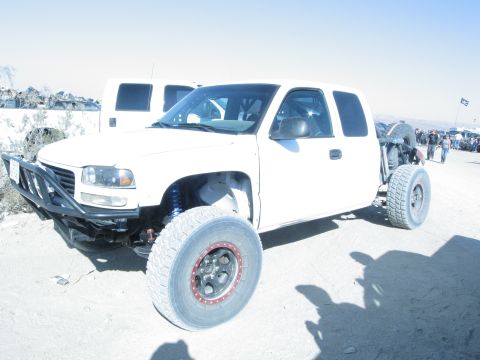 1986 Ford Bronco - Modified pickup truck with off-road tires and bumper is parked outdoors with other vehicles.