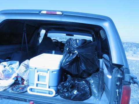 1986 Ford Bronco - The rear of an SUV is packed with trash bags and a cooler, suggesting a clean-up effort.
