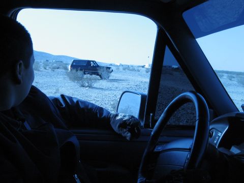 1986 Ford Bronco - Looking out from a vehicle at a Ford Bronco in a dry, dusty landscape.