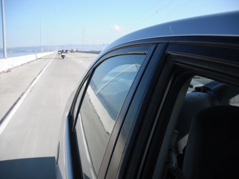 1991 Ford Bronco - View from inside a car on a highway, with several motorcycles ahead and a city in the distance under a clear blue sky.