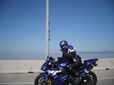 1991 Ford Bronco - Rider on a blue sport motorcycle on a bridge with water and land in the background.