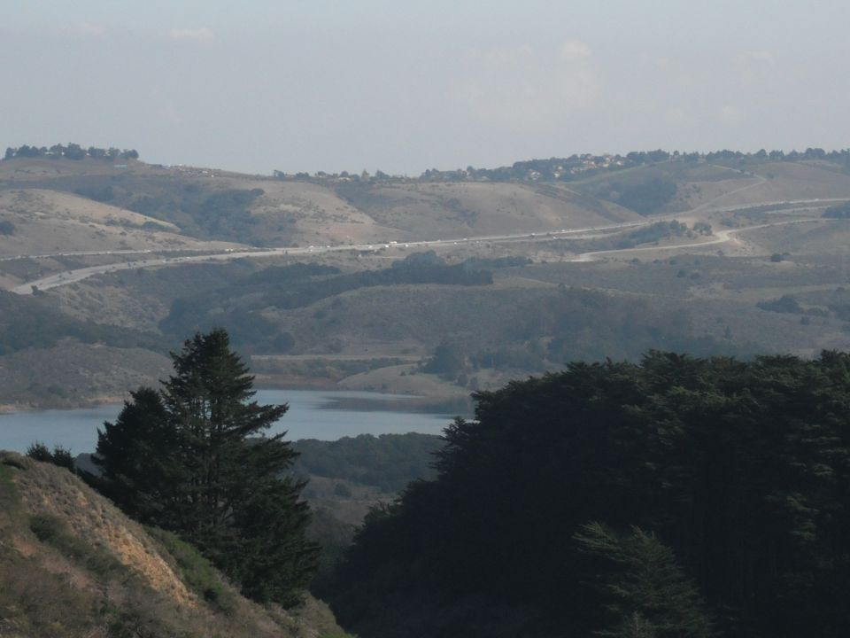 Hilly landscape with a lake and a highway in the distance