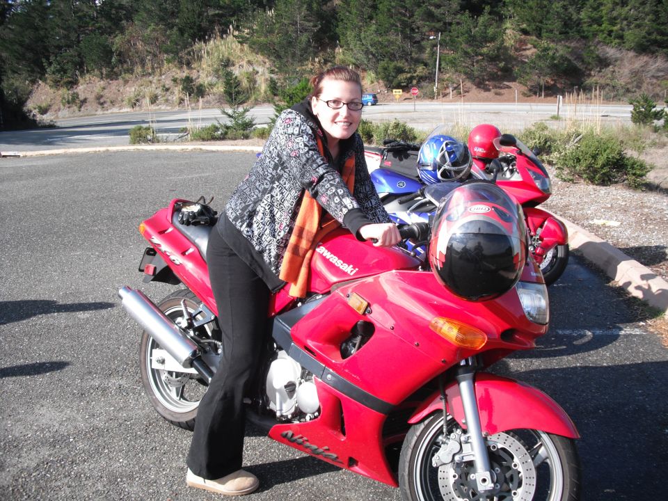 Woman posing on a red Kawasaki Ninja motorcycle with two other motorcycles behind her