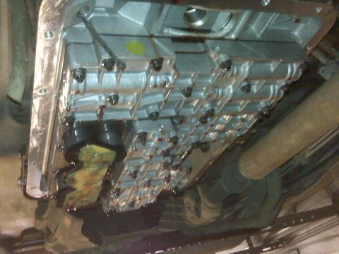 1994 Ford F-150 - The transmission pan shows signs of wear and fluid seepage.