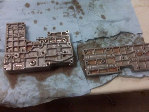1994 Ford F-150 - Two metal transmission valve body components are laid out on a stained blue shop towel.