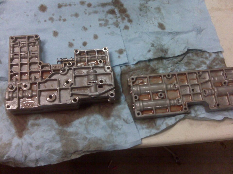 Transmission valve body parts on a blue shop towel with oil stains