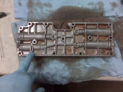 1994 Ford F-150 - A gloved hand points to a slot on a metal valve body, which appears to be part of a transmission.