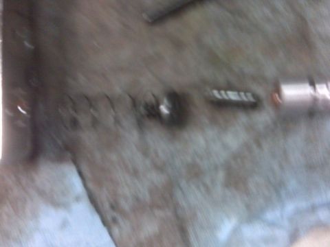 1994 Ford F-150 - A blurry close-up shows a spring and a metal component, likely a part from a vehicle.