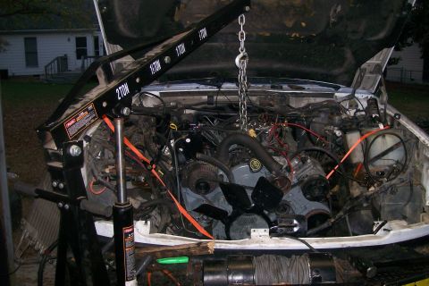 1992 Ford C-350 (Centurion Conversions) - Engine bay of a Ford truck with an engine hoist attached, undergoing maintenance.
