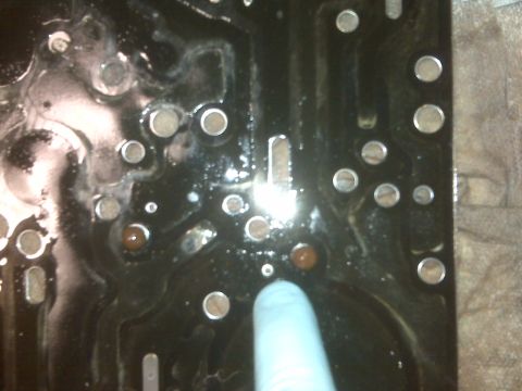 1994 Ford F-150 - A close-up view of a transmission valve body, possibly from a Ford F-150, shows intricate metalwork and fluid residue.