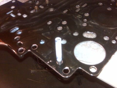 1994 Ford F-150 - Close-up of a transmission pan gasket, showing its intricate design with various holes and a visible spring.