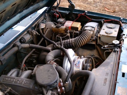 1996 Ford Bronco - The engine bay features a prominent supercharger and a complex network of hoses and wiring.