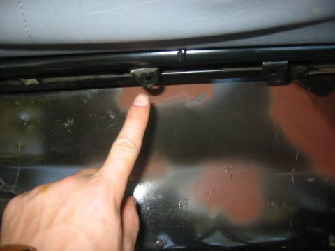 1995 Ford Bronco - A finger points to a seat bracket inside a vehicle.