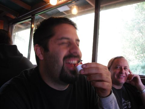 1991 Ford Bronco - Two men are seated indoors, possibly at a restaurant, with one man in the foreground laughing while eating.