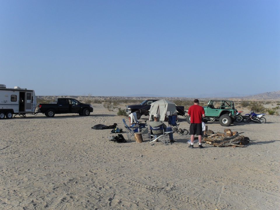 Desert camp with travel trailer, pickups and off-road vehicles