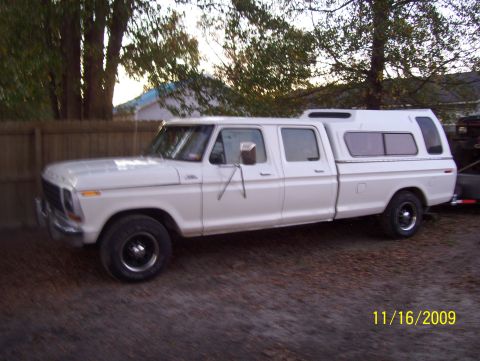 1978 Ford Bronco - A white Ford crew cab pickup truck shown in side/three-quarter front profile, fitted with a matching white camper shell over the bed, parke…