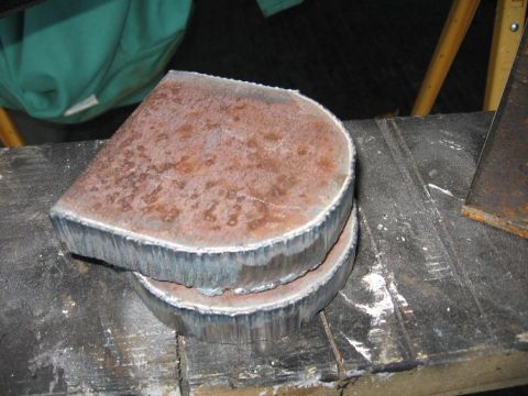 1995 Ford F-150 - Two circular metal pieces, likely cut from a larger object, are stacked on a workbench. The top piece shows signs of rust.