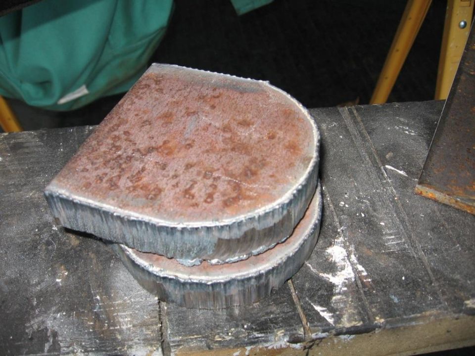 two cut metal pieces stacked on a workbench