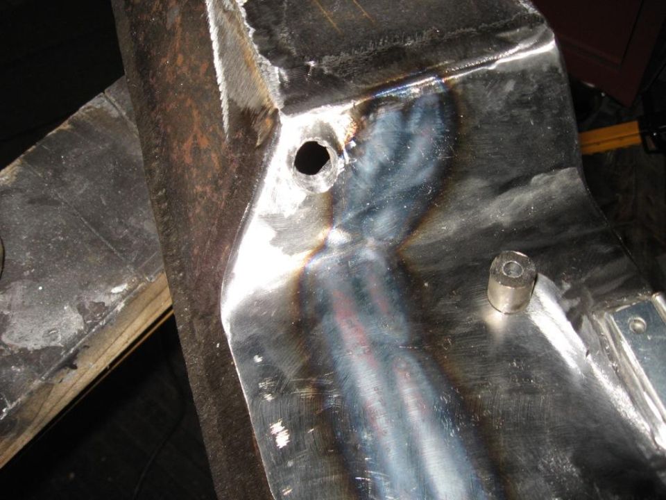 Close-up of a shiny metal bumper part with a bolt and a hole