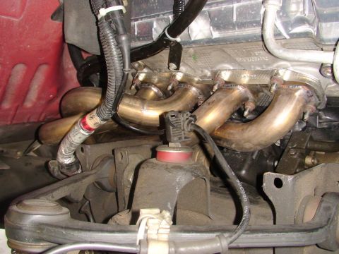 2007 Ford Mustang - Close-up view of an engine's exhaust manifold, showing the complex pipework and associated engine components.