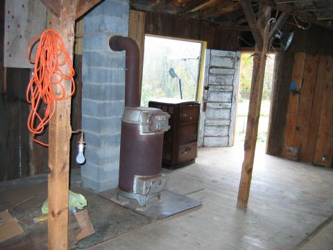 1992 Ford Bronco - The interior of a rustic building contains a wood-burning stove and an orange extension cord hanging from a wooden beam.