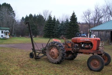 2000 Chevrolet Tahoe - An old Allis-Chalmers tractor with a mower is parked outside a rustic building.