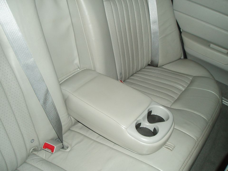 Light tan leather rear seat with armrest and cup holders. 2003 Ford Crown Victoria