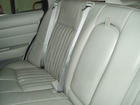 2003 Ford Crown Victoria - The interior of a car shows the back seat and door panel, with a watermark for Supermotors.net.