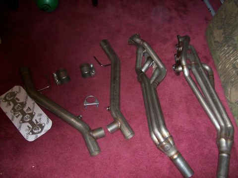 2007 Ford Mustang - Aftermarket exhaust headers and associated piping components are displayed on a carpeted surface.