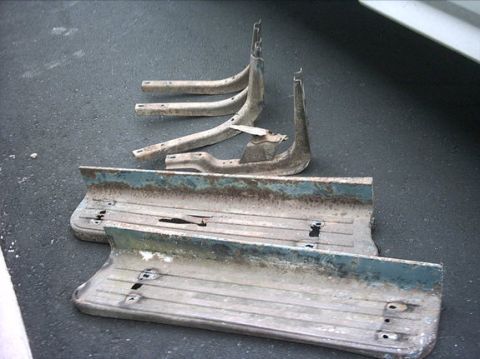 1954 Ford F-100 - Weathered truck running boards and mounting brackets lie on a dark asphalt surface.