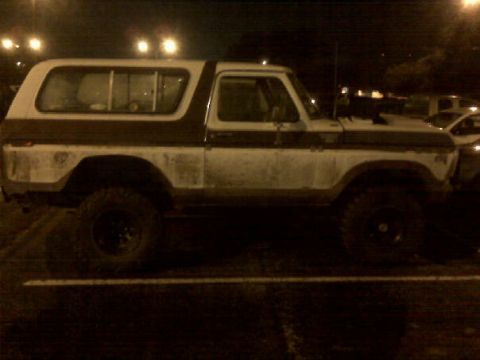 1979 Ford Bronco - A classic Ford Bronco is seen parked in a lot at night, illuminated by streetlights.