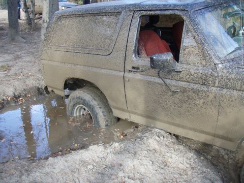 1985 Ford Bronco - This SUV is stuck deep in the mud, with another vehicle visible in the background.