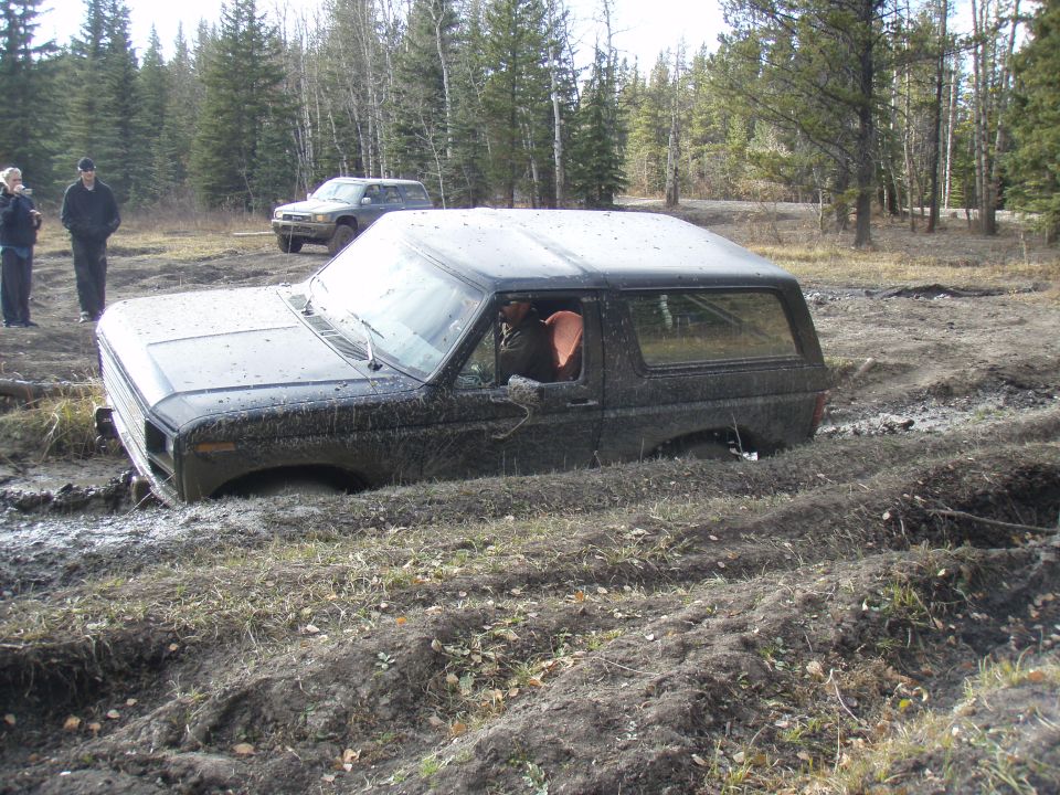 Black 1980s Ford Bronco stuck in mud, front 3/4 view