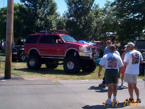 1978 Ford Bronco - A heavily modified red SUV with large tires is displayed outdoors.