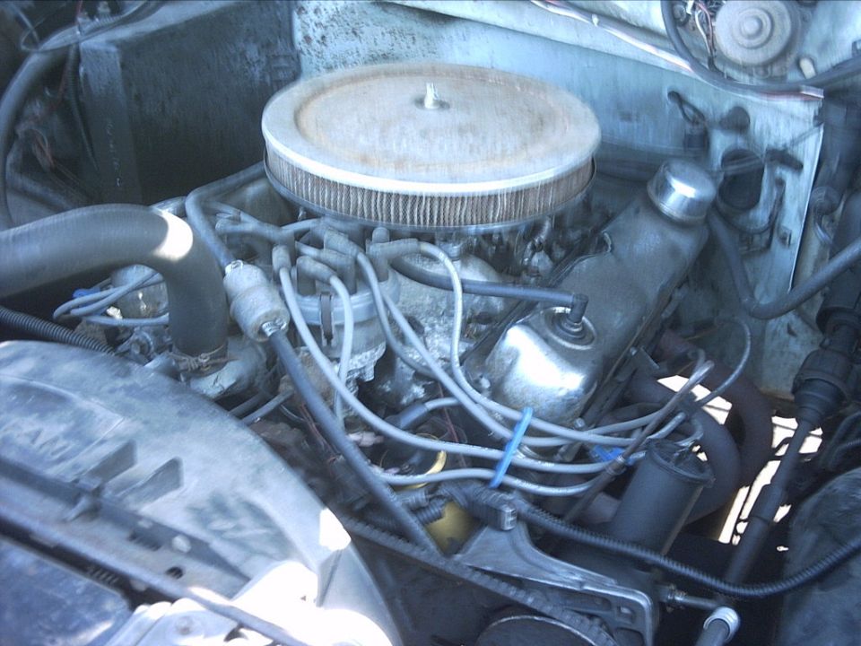 Engine bay of an older vehicle with round air cleaner