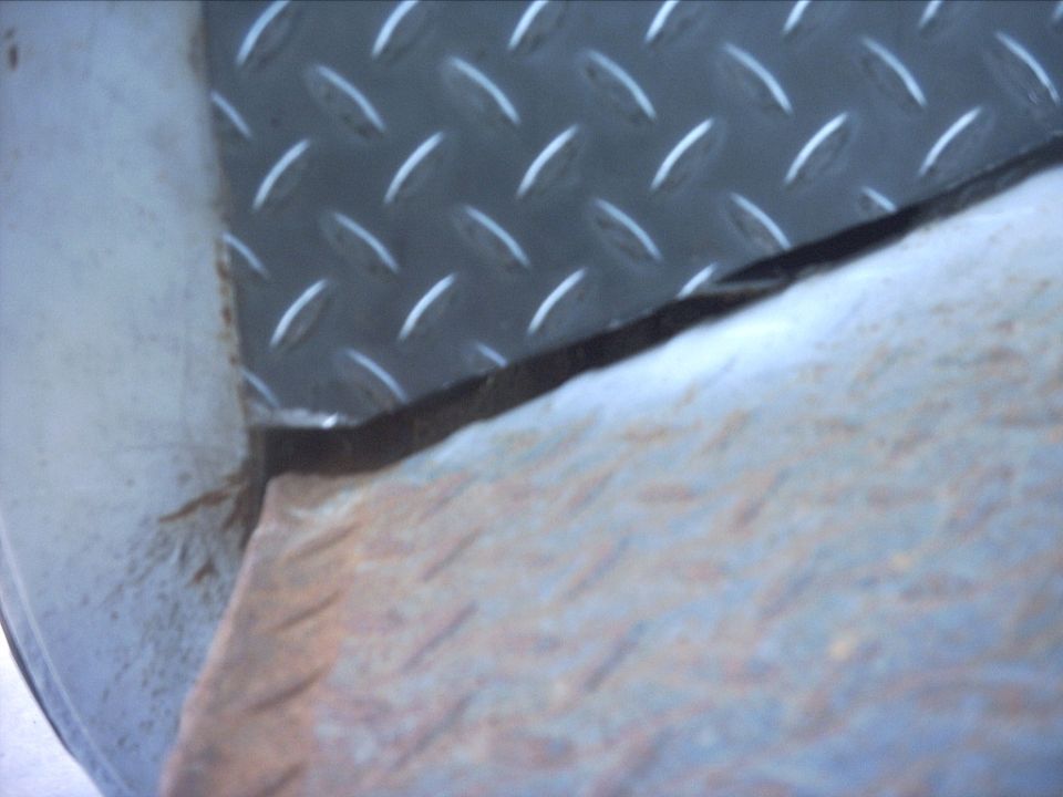 Close-up of diamond-plate flooring with rusty edge